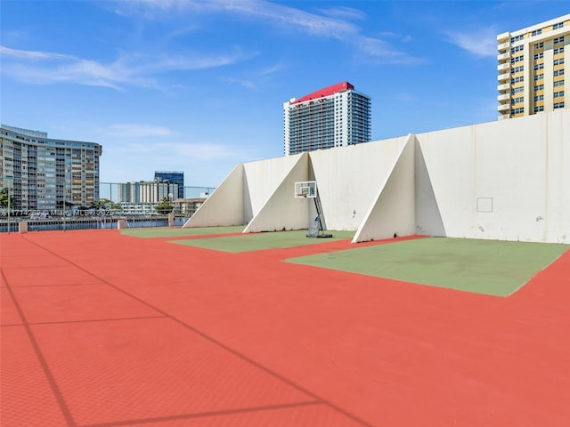 surrounding community featuring community basketball court, fence, and a city view