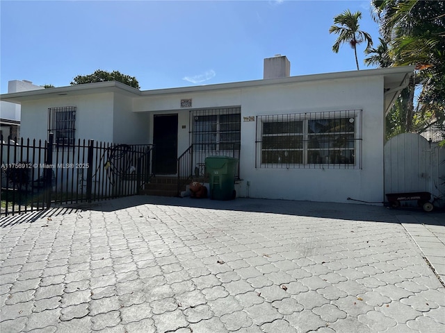 view of front of home with fence, a chimney, and stucco siding