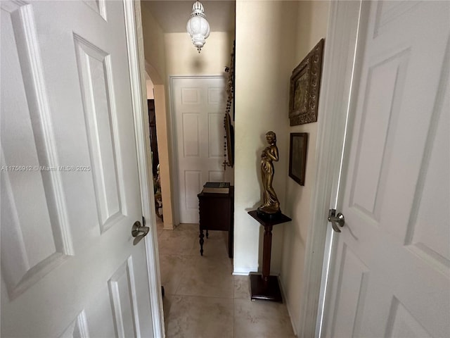 hallway featuring arched walkways and light tile patterned floors