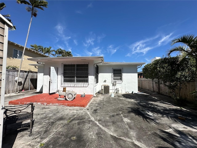 rear view of house with central AC unit, a patio area, fence, and stucco siding