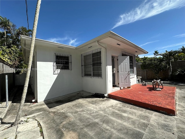 exterior space featuring a patio area, fence, and stucco siding