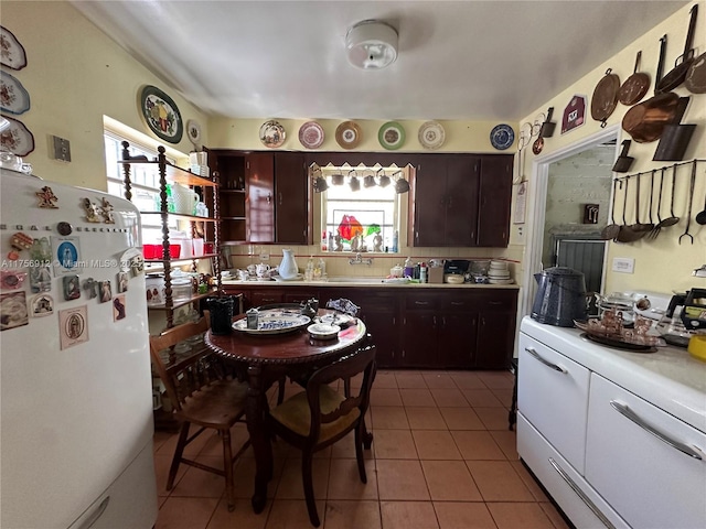 kitchen with a healthy amount of sunlight, light tile patterned floors, light countertops, and freestanding refrigerator