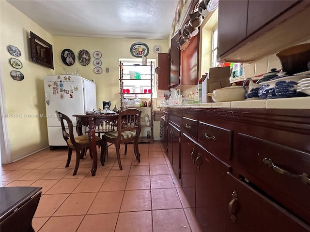 kitchen with tile counters, freestanding refrigerator, and light tile patterned floors