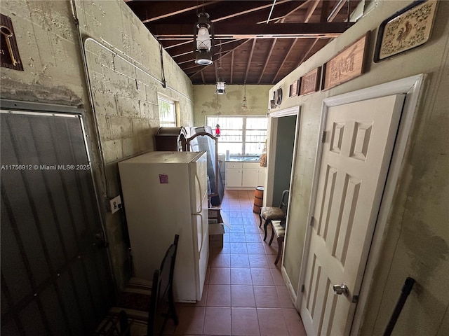 kitchen featuring lofted ceiling, tile patterned flooring, and freestanding refrigerator