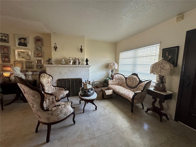 sitting room with a textured ceiling and a tiled fireplace