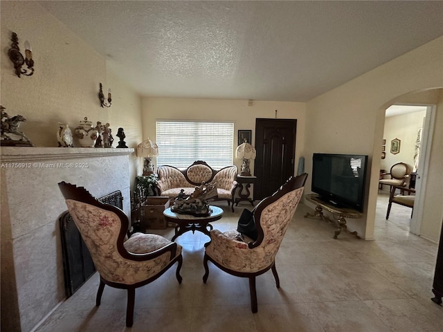 sitting room with arched walkways, a textured ceiling, and a fireplace