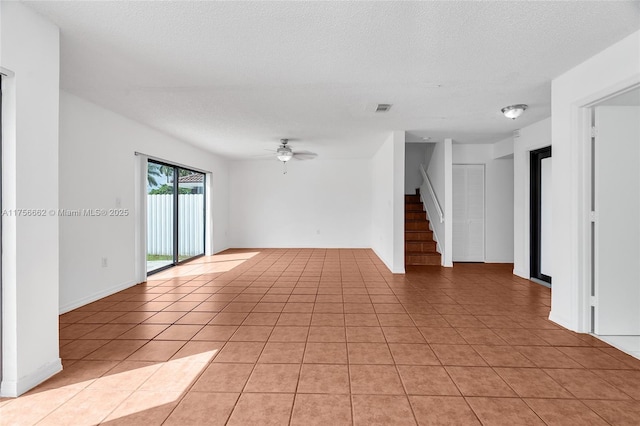 unfurnished room featuring light tile patterned floors, visible vents, stairway, a ceiling fan, and a textured ceiling