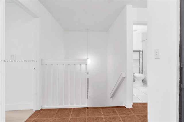 hallway with tile patterned flooring and an upstairs landing