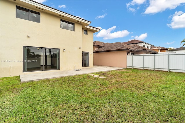 back of house featuring a lawn, fence, and stucco siding