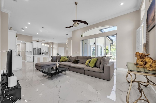 living room with marble finish floor, ornamental molding, a ceiling fan, and baseboards