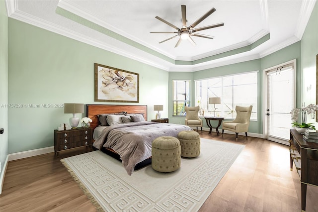 bedroom featuring light wood-style flooring, a tray ceiling, access to outside, and ornamental molding