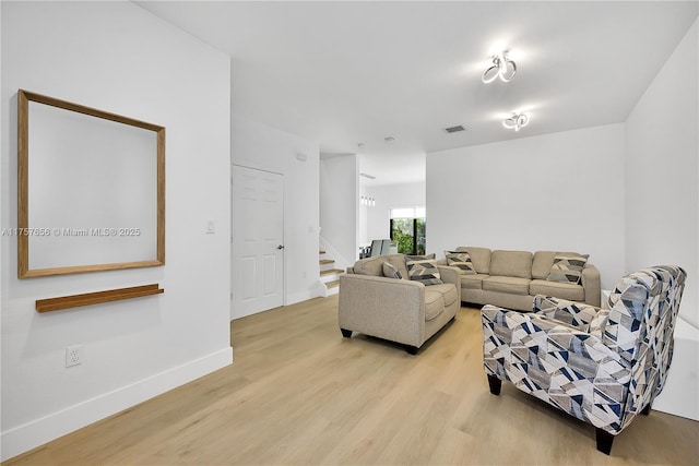 living area with visible vents, baseboards, light wood-style floors, and stairs