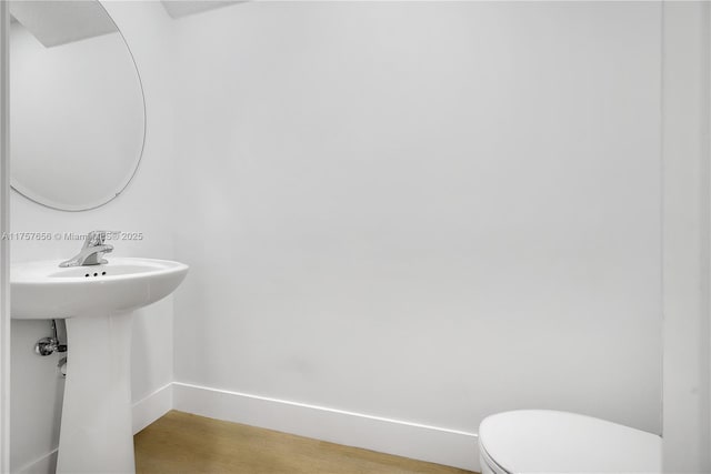 bathroom featuring a sink, toilet, baseboards, and wood finished floors