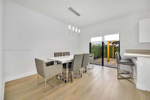 dining area with baseboards, light wood finished floors, and built in desk