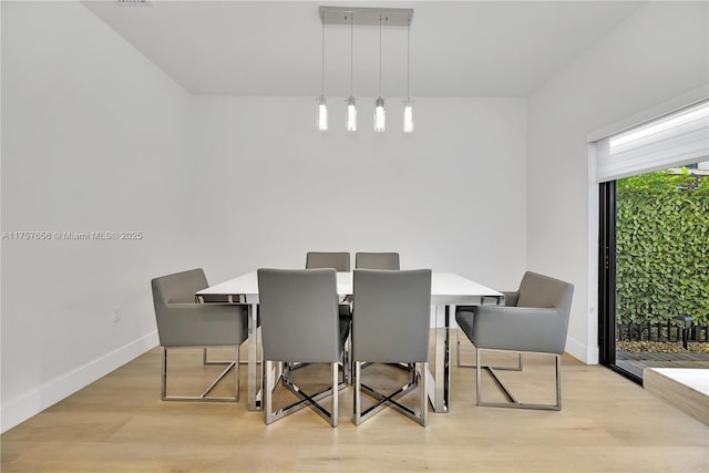 dining space with baseboards and light wood-style flooring