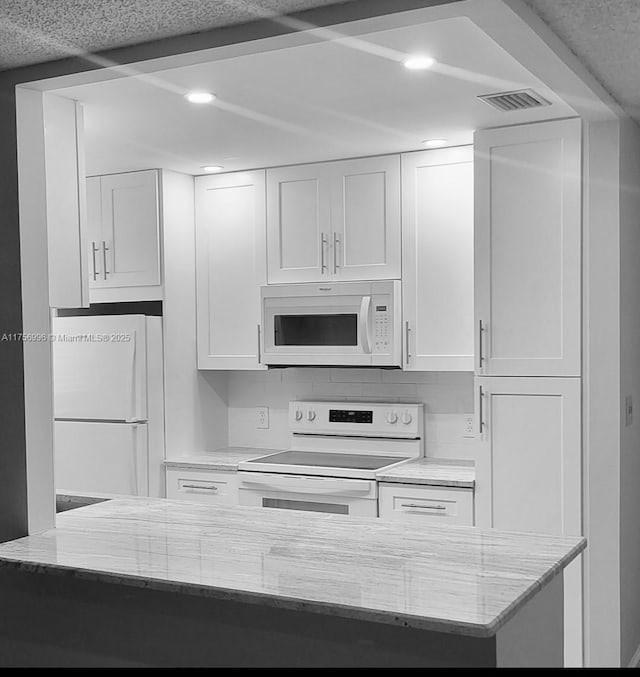 kitchen featuring light stone counters, recessed lighting, white appliances, visible vents, and white cabinetry