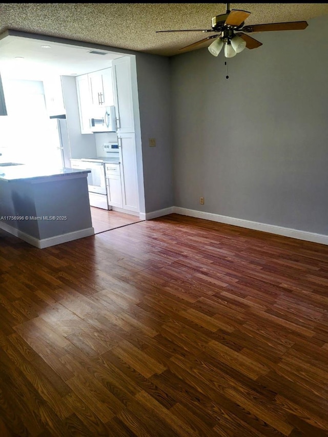 unfurnished living room featuring dark wood-style floors, visible vents, a sink, and baseboards