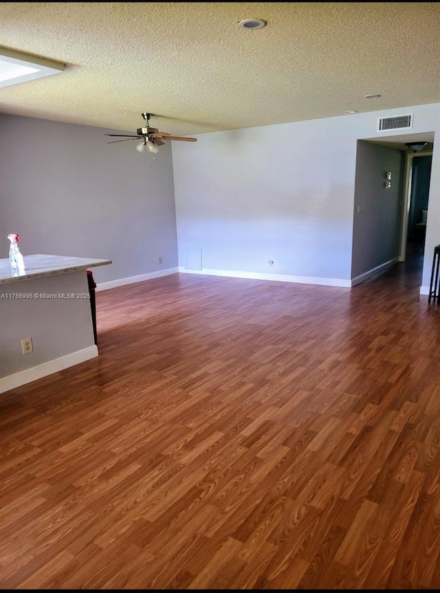 unfurnished room featuring ceiling fan, a textured ceiling, wood finished floors, and visible vents