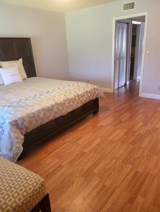 bedroom featuring light wood-type flooring, visible vents, and baseboards