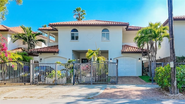 view of front of house with decorative driveway, a tile roof, stucco siding, a gate, and fence