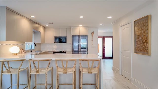 kitchen with stainless steel appliances, a breakfast bar, a peninsula, a sink, and light countertops