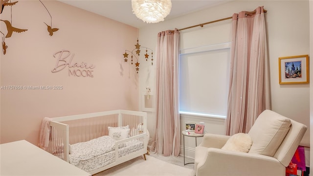 bedroom featuring a chandelier and a nursery area