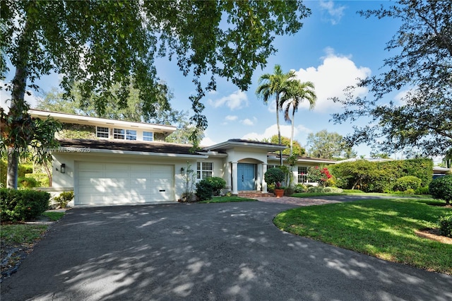 view of front facade featuring aphalt driveway, a front yard, a garage, and stucco siding