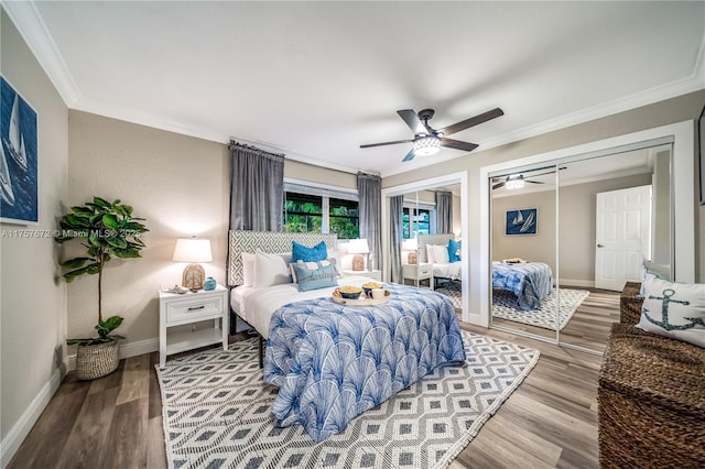 bedroom featuring ornamental molding, wood finished floors, baseboards, and two closets