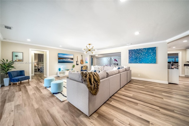 living room featuring ornamental molding, light wood-type flooring, visible vents, and baseboards