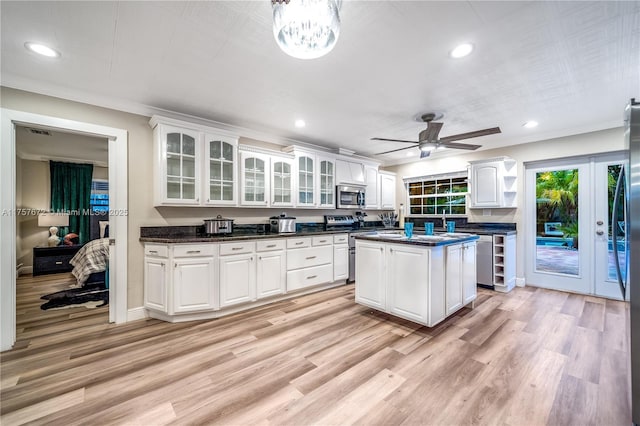 kitchen featuring dark countertops, stainless steel appliances, light wood-style floors, white cabinetry, and open shelves