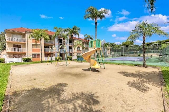 community jungle gym featuring a tennis court and fence