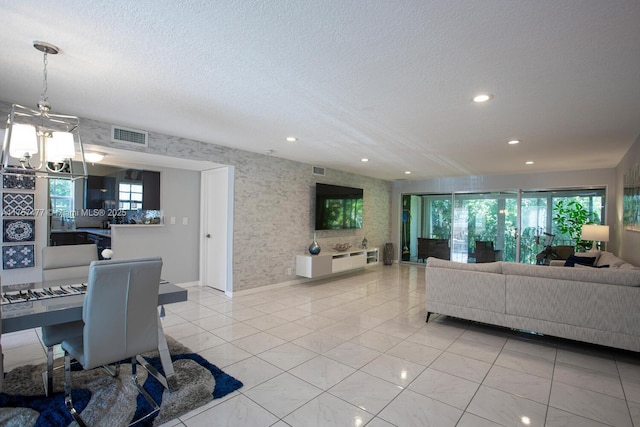 living area featuring a textured ceiling, light tile patterned flooring, visible vents, and a notable chandelier