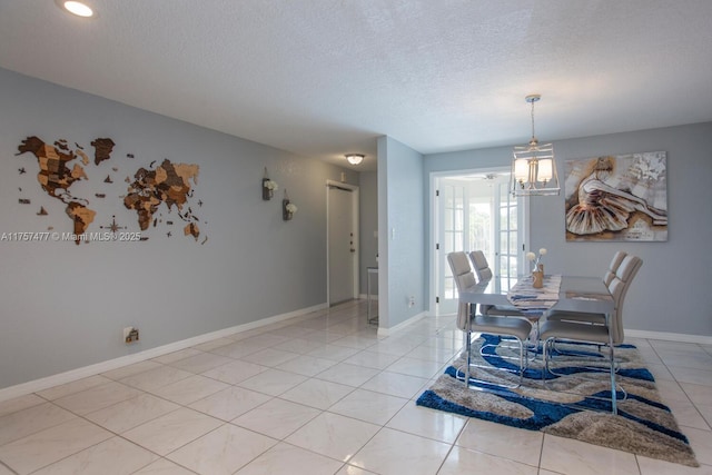 dining room with a textured ceiling, light tile patterned floors, a notable chandelier, and baseboards