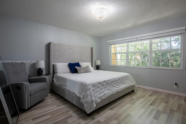 bedroom featuring a textured ceiling, light wood finished floors, and baseboards