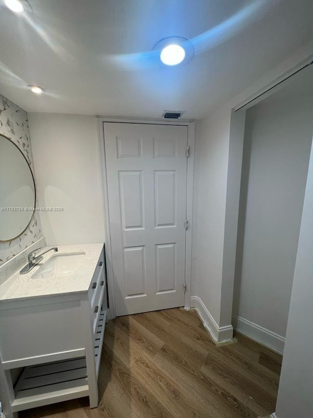 bathroom with visible vents, baseboards, wood finished floors, and vanity