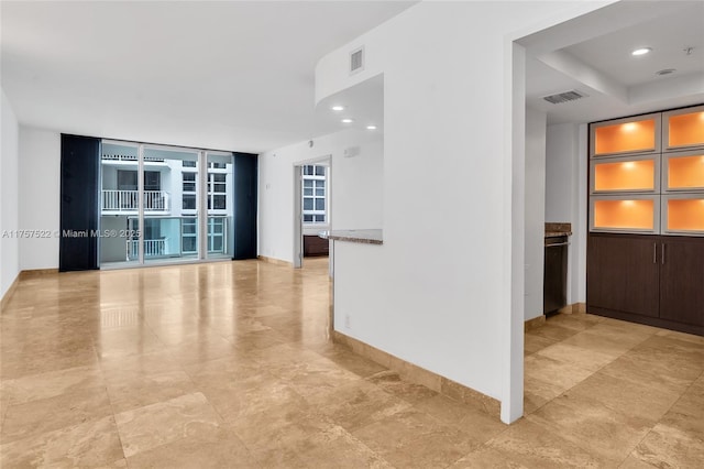 spare room featuring baseboards, floor to ceiling windows, visible vents, and recessed lighting