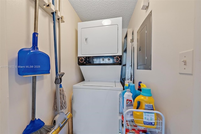 laundry room featuring stacked washer and clothes dryer, electric panel, a textured ceiling, and laundry area