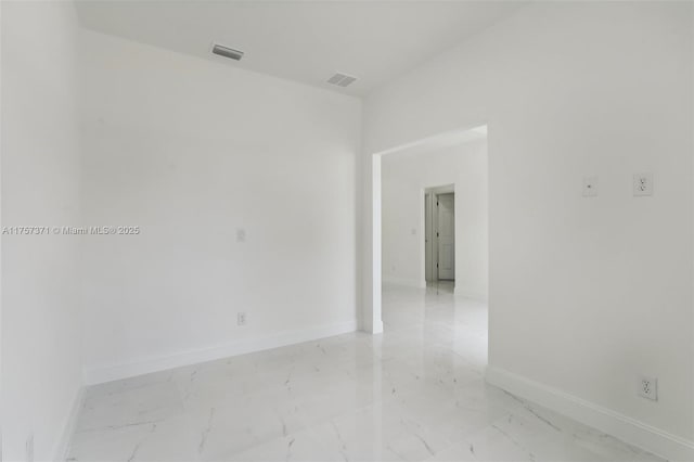 empty room with marble finish floor, visible vents, and baseboards