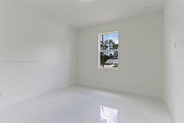 unfurnished room featuring marble finish floor and baseboards