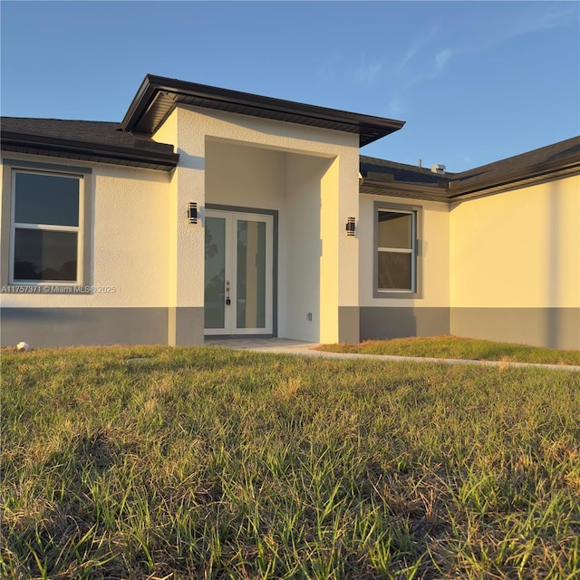 property entrance featuring stucco siding and french doors