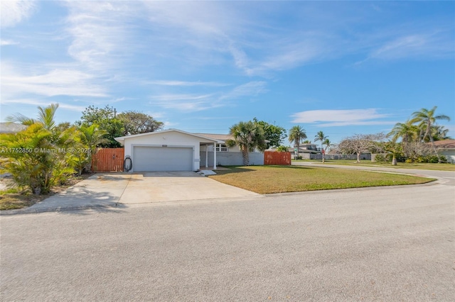 ranch-style house with an attached garage, fence, concrete driveway, a gate, and a front lawn