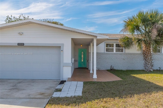 ranch-style home with driveway, an attached garage, a front yard, stucco siding, and brick siding