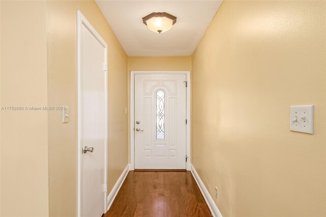 doorway featuring dark wood-style floors and baseboards