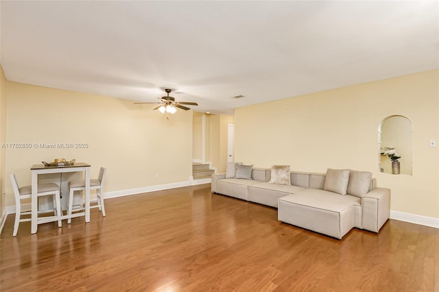 living room featuring a ceiling fan, visible vents, baseboards, and wood finished floors