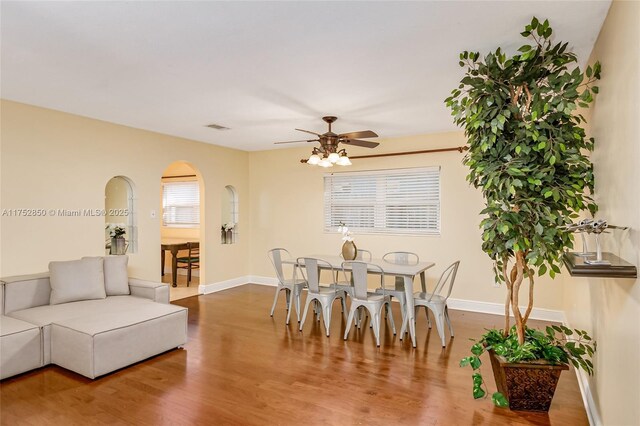 dining room featuring a ceiling fan, visible vents, baseboards, and wood finished floors