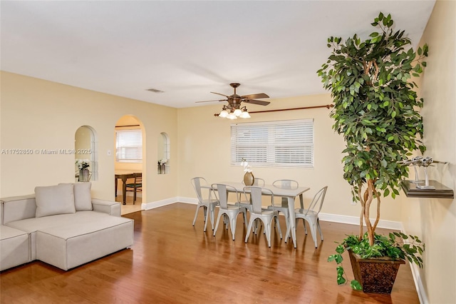interior space with arched walkways, wood finished floors, baseboards, and ceiling fan