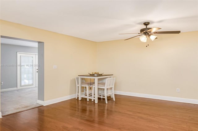 unfurnished dining area featuring ceiling fan, baseboards, and wood finished floors