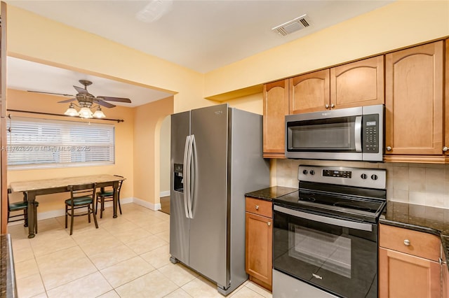 kitchen with arched walkways, visible vents, decorative backsplash, a ceiling fan, and appliances with stainless steel finishes