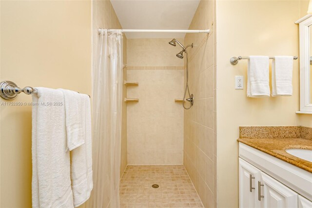 full bath featuring a tile shower and vanity