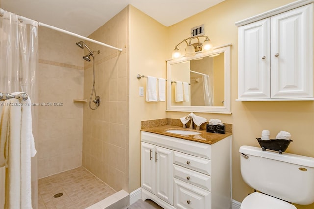 full bathroom featuring visible vents, tiled shower, vanity, and toilet